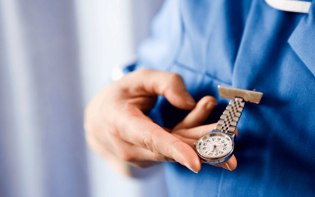 Person, die auf Schwestern-/Pflegeuhr guckt