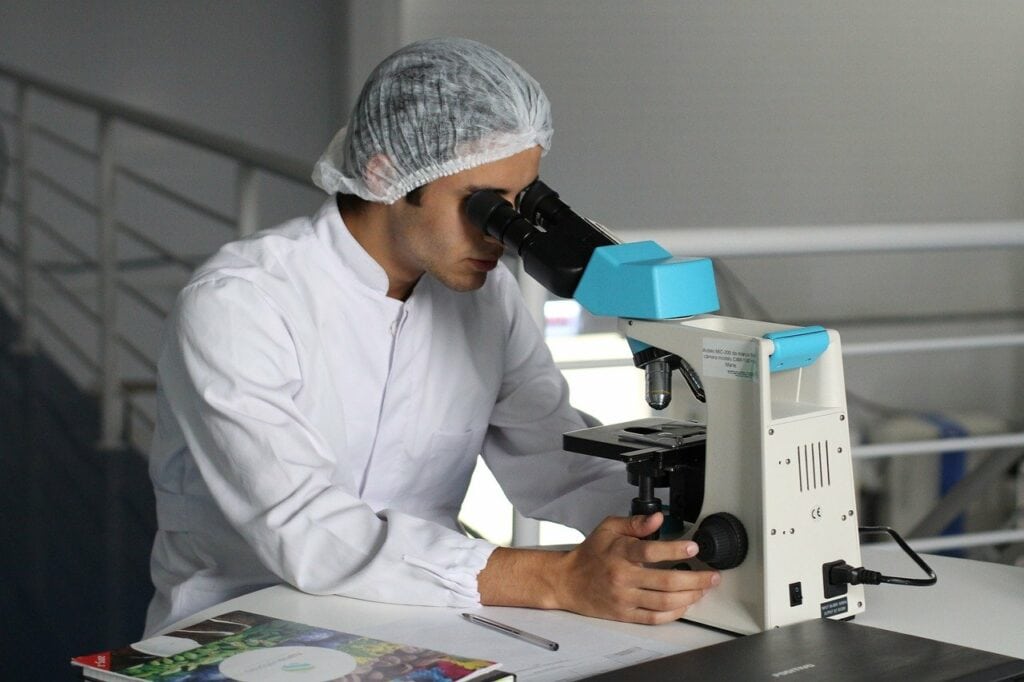 Laborarbeiter mikroskopiert etwas.