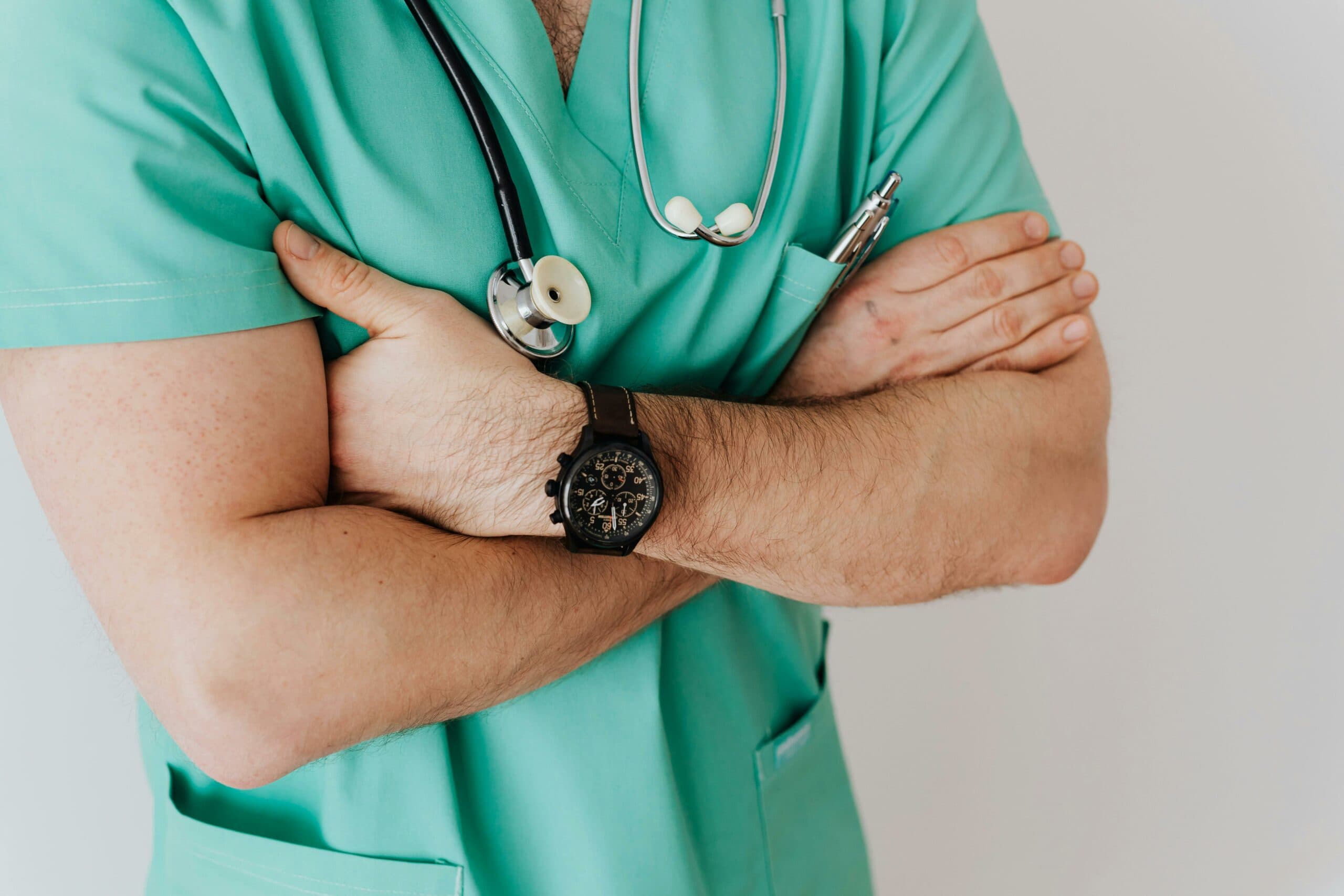 Ein medizinischer Angestellter in Arbeitskleidung, der eine Armbanduhr trägt.